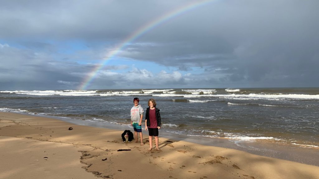 learners at beach with a rainbow behind them