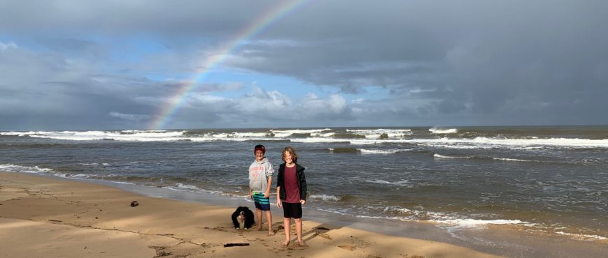 learners at beach with a rainbow behind them
