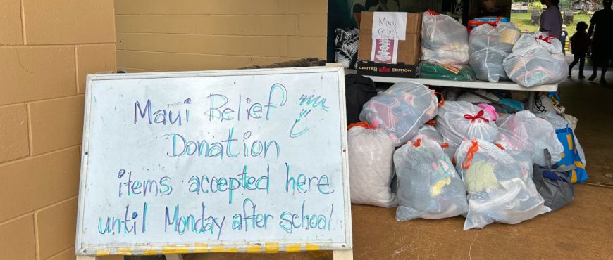 white board with a message about Maui Donation Relief and several full bags of donations in the background