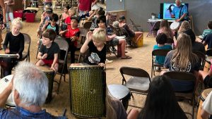 2 side by side images of young AOK learners drumming during a special drumming class