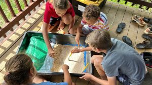 group of 4 AOK engaged in a hand-ons activity with sand and paintbrushes
