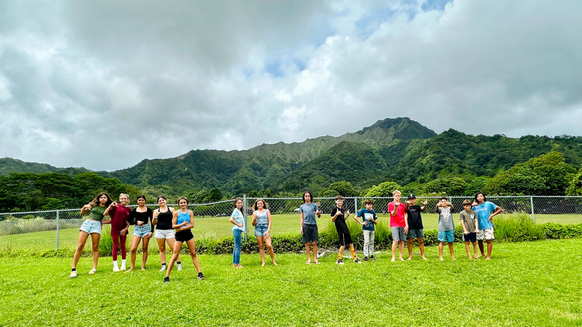 AOK Cross Country learners standing in a green field with a large mountain in the background